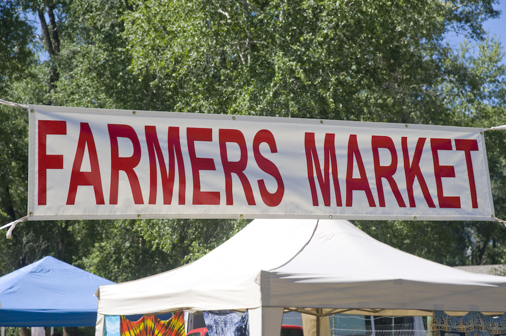Farmers market sign hanging over booths